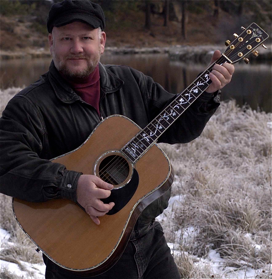 Ron Meyers with his acoustic guitar by the river